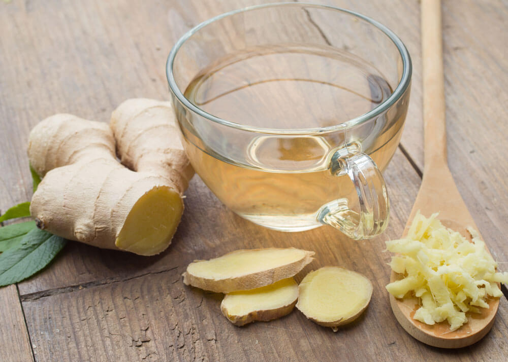 Close-up of raw ginger root and a cup of ginger tea.