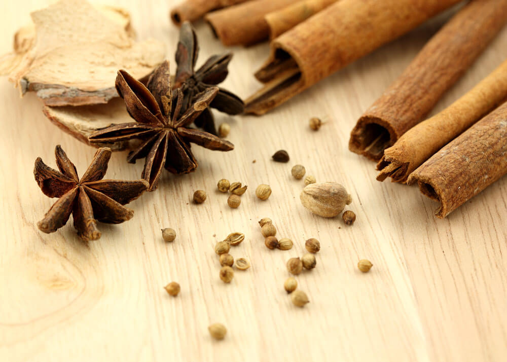 Close-up of cinnamon sticks and star anise pods on a table.